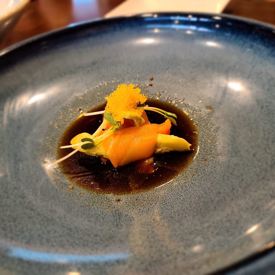 Ginger Bistro's sushi appetizer features salmon, avocado, microgreens, and orange tobiko in a dark sauce.